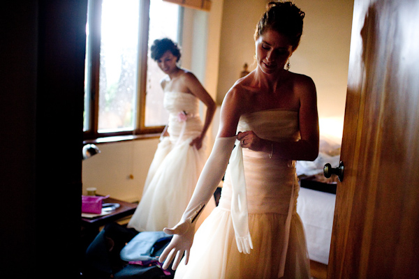 bridesmaids getting ready for the ceremony - bridesmaids are wearing mermaid style light pink dresses and putting on white elbow length gloves - photo by New Mexico based wedding photographers Twin Lens